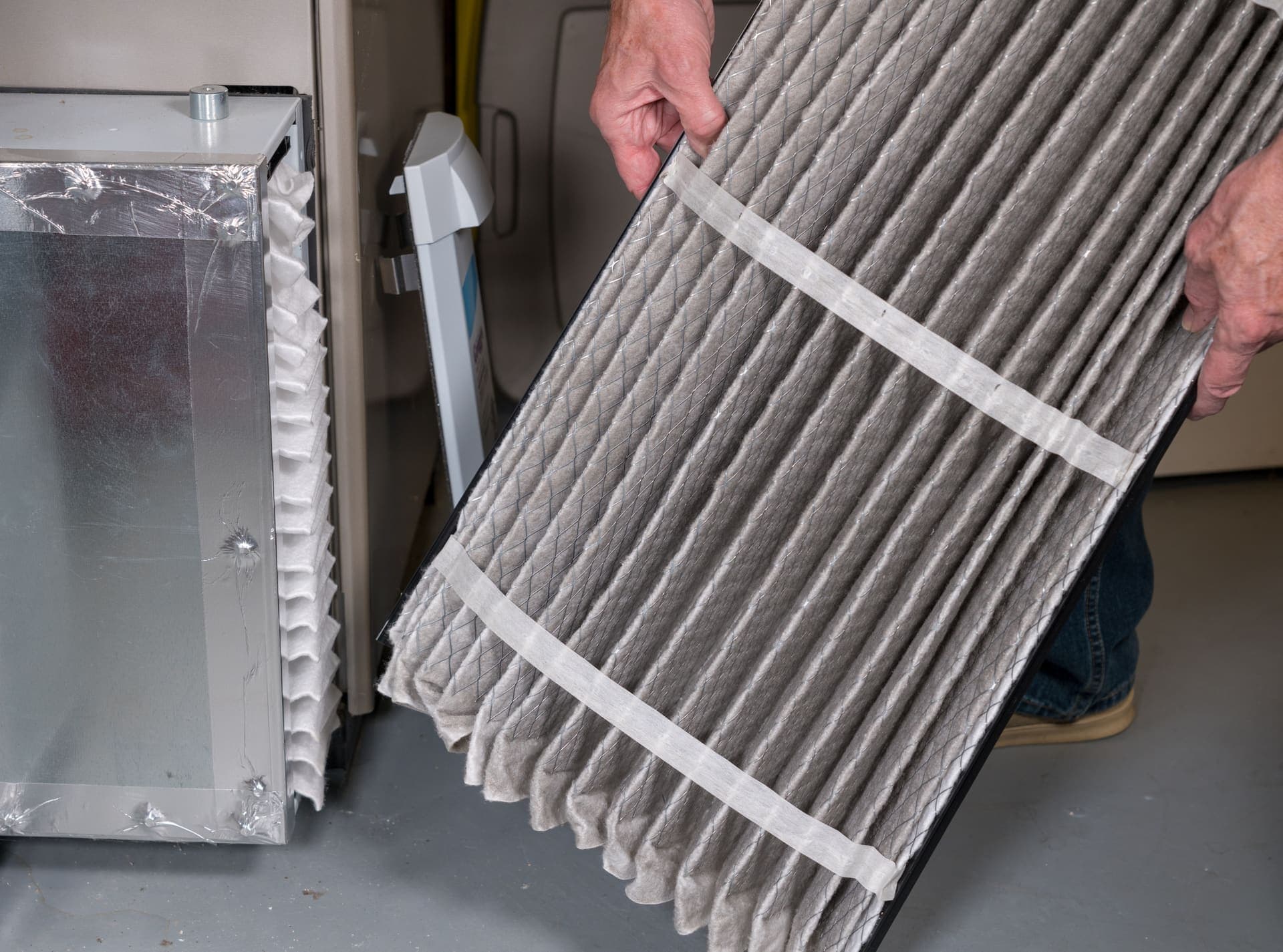A dirty air filter being taken out of a home's air handler