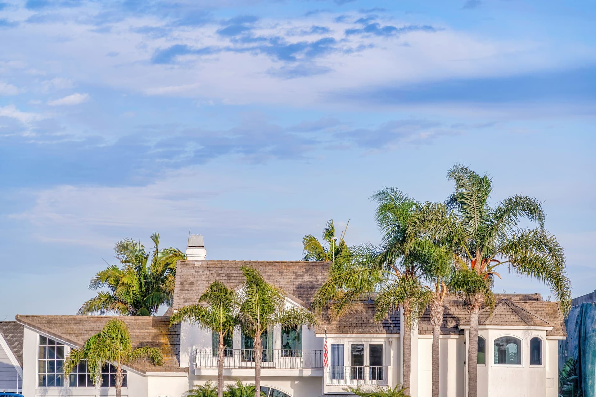 A white South Florida home with tall palm trees under a blue sky